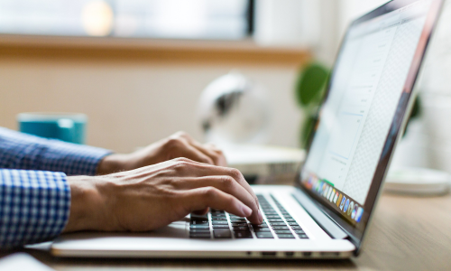 A closeup of hands typing on a laptop.